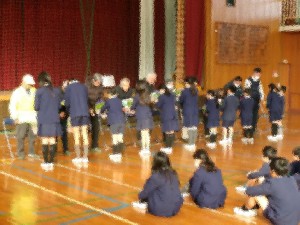 子どもたちがボランティアの人たちに鉢植えの花をプレゼントしています